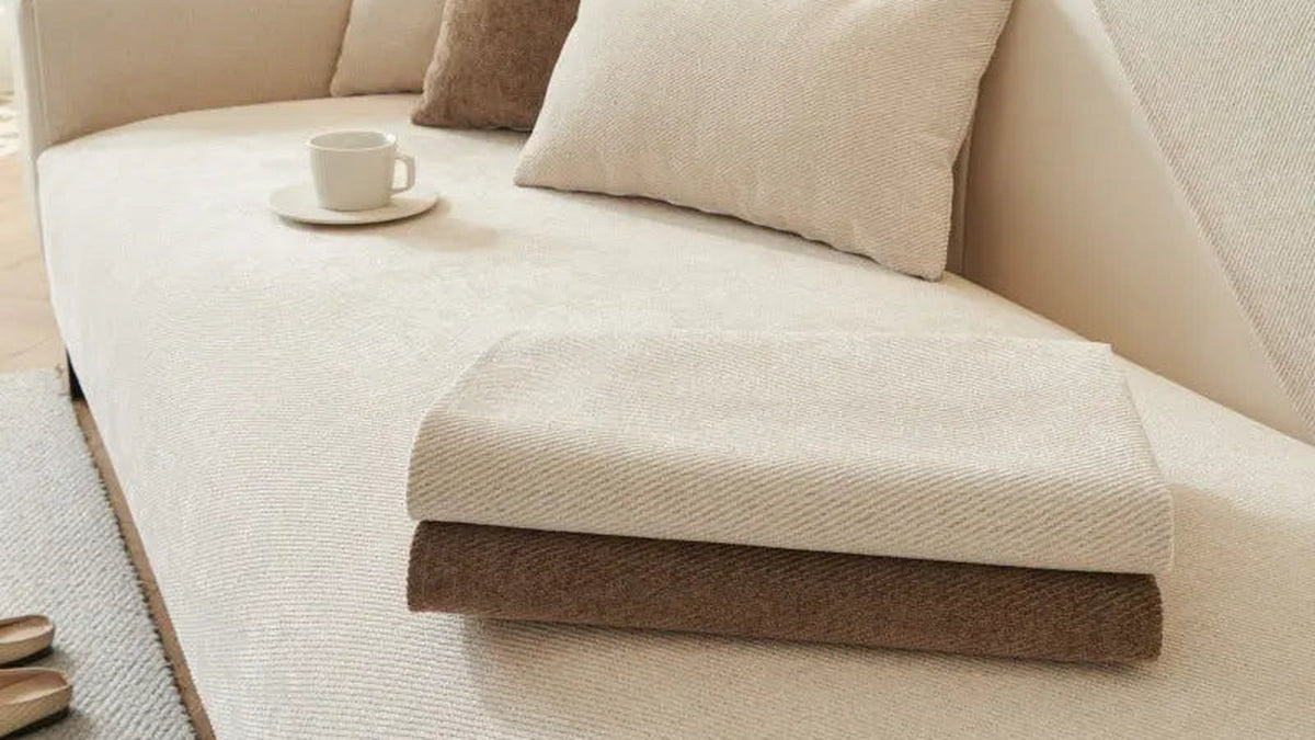 Cream chenille pet protection sofa cover with a folded second cover on a bright living room sofa